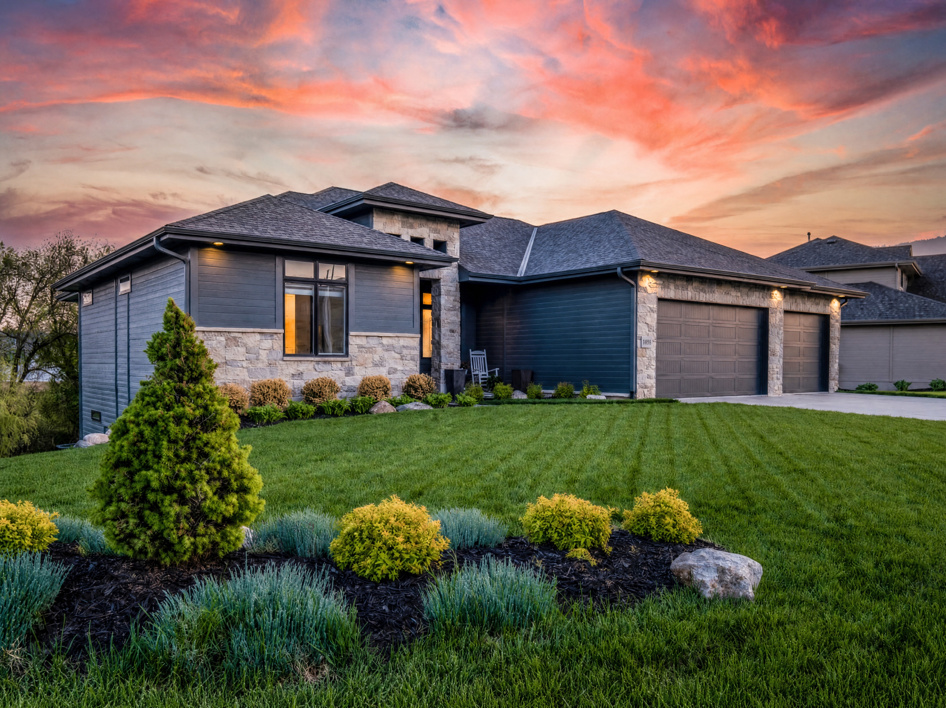 A modern home at sunset with professionally landscaped gardens and lawn